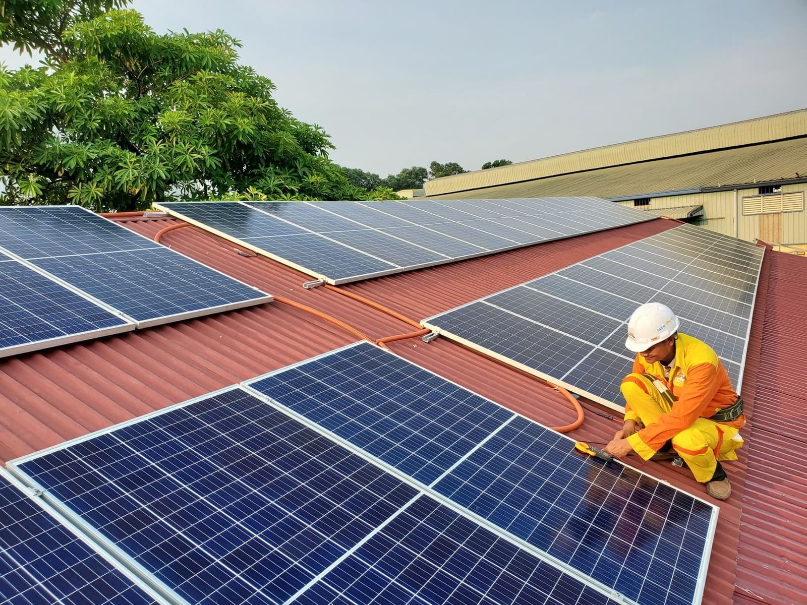 Installer kneeling on a roof among solar panels