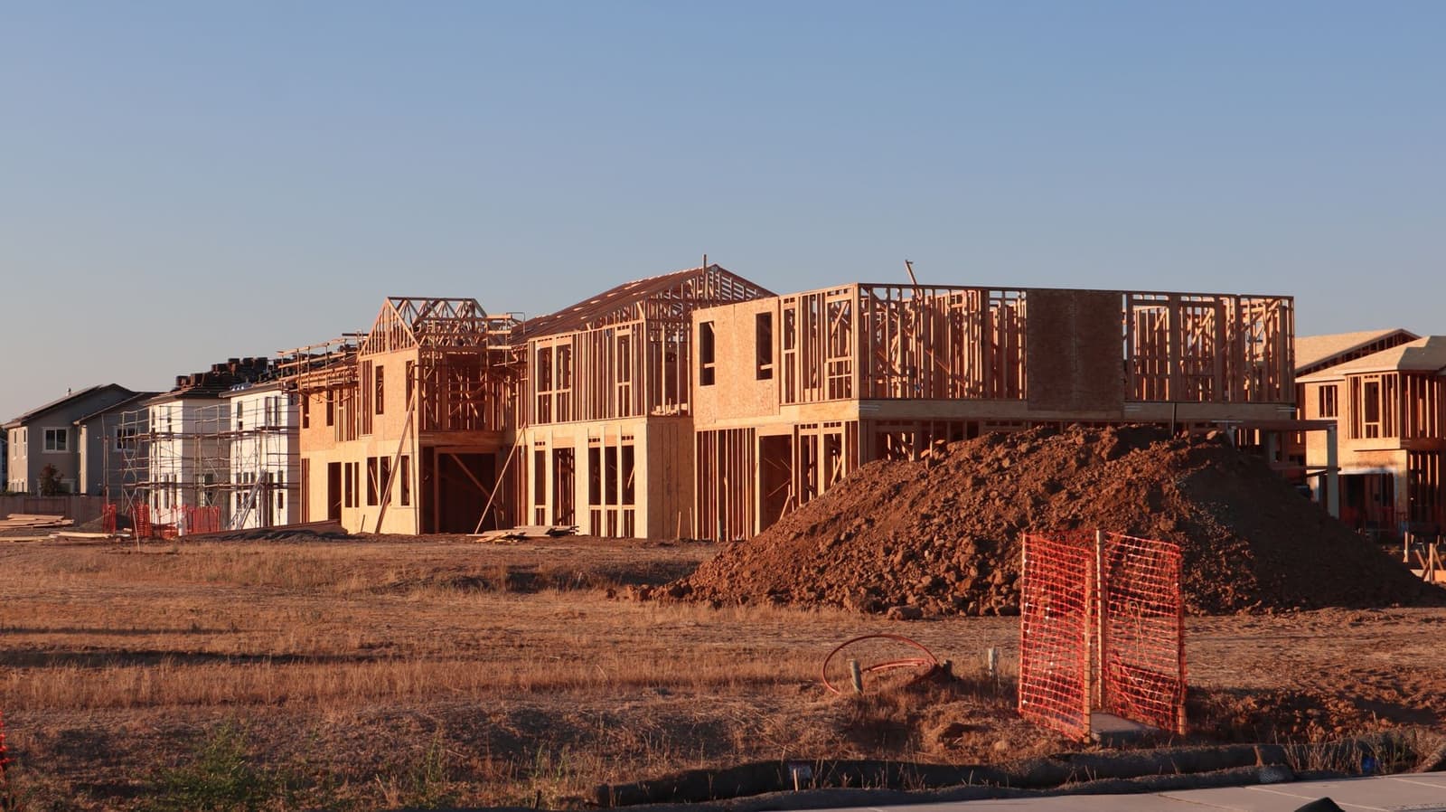 Row of wood-framed houses under construction at sunset
