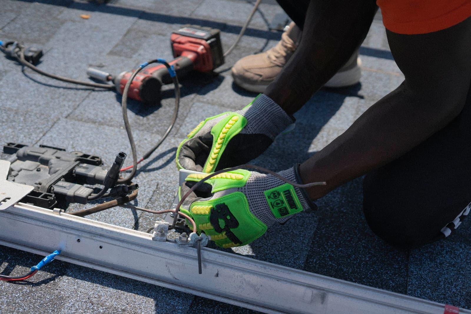 Gloved hands installing solar rails on a shingle roof