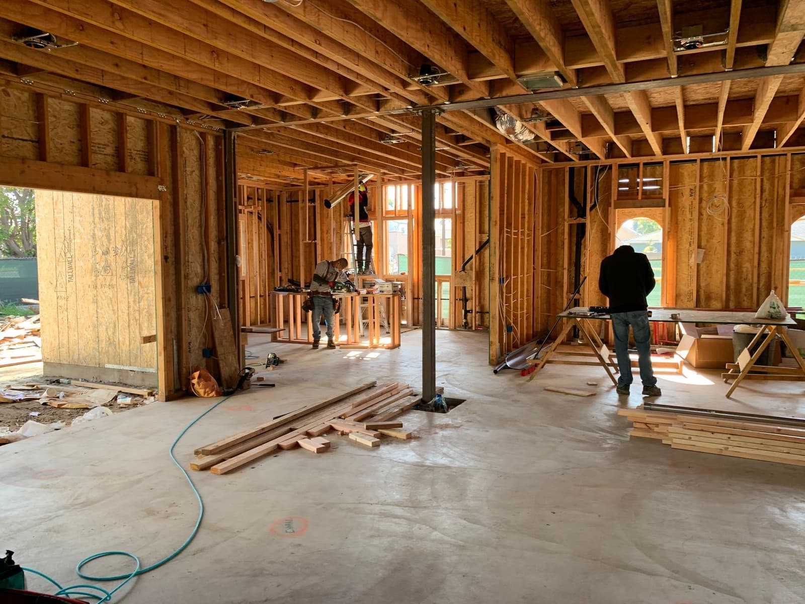 Workers inside wood-framed house under construction