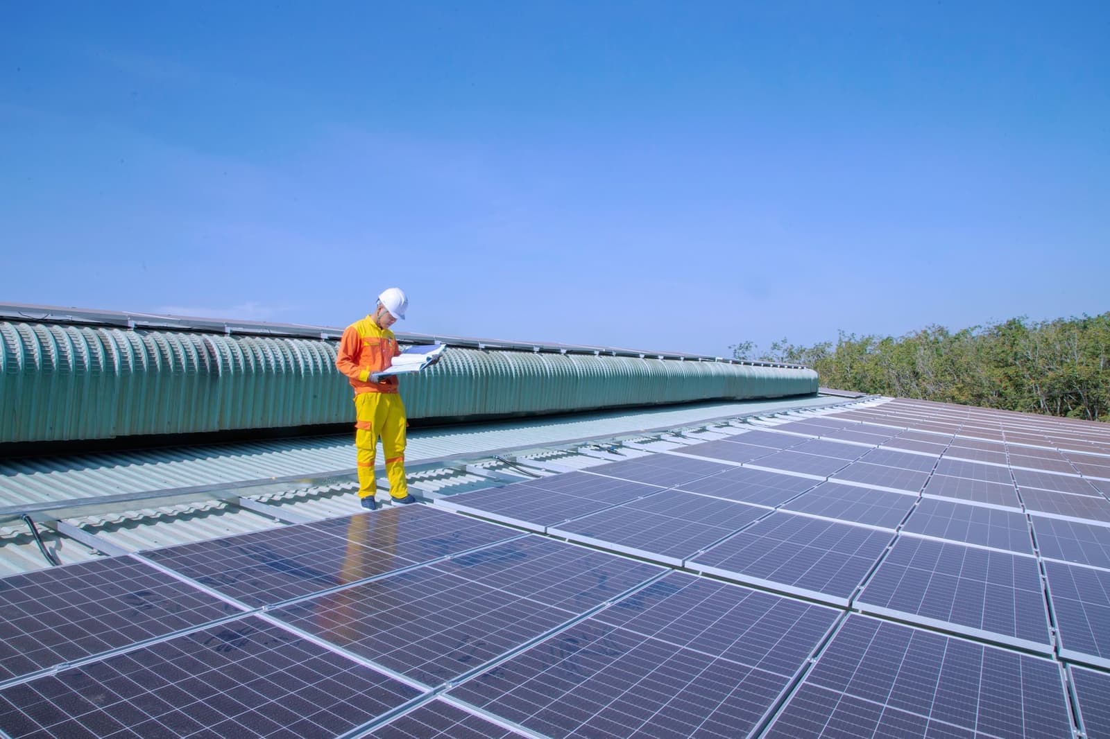 Worker on a large commercial roof with solar panels