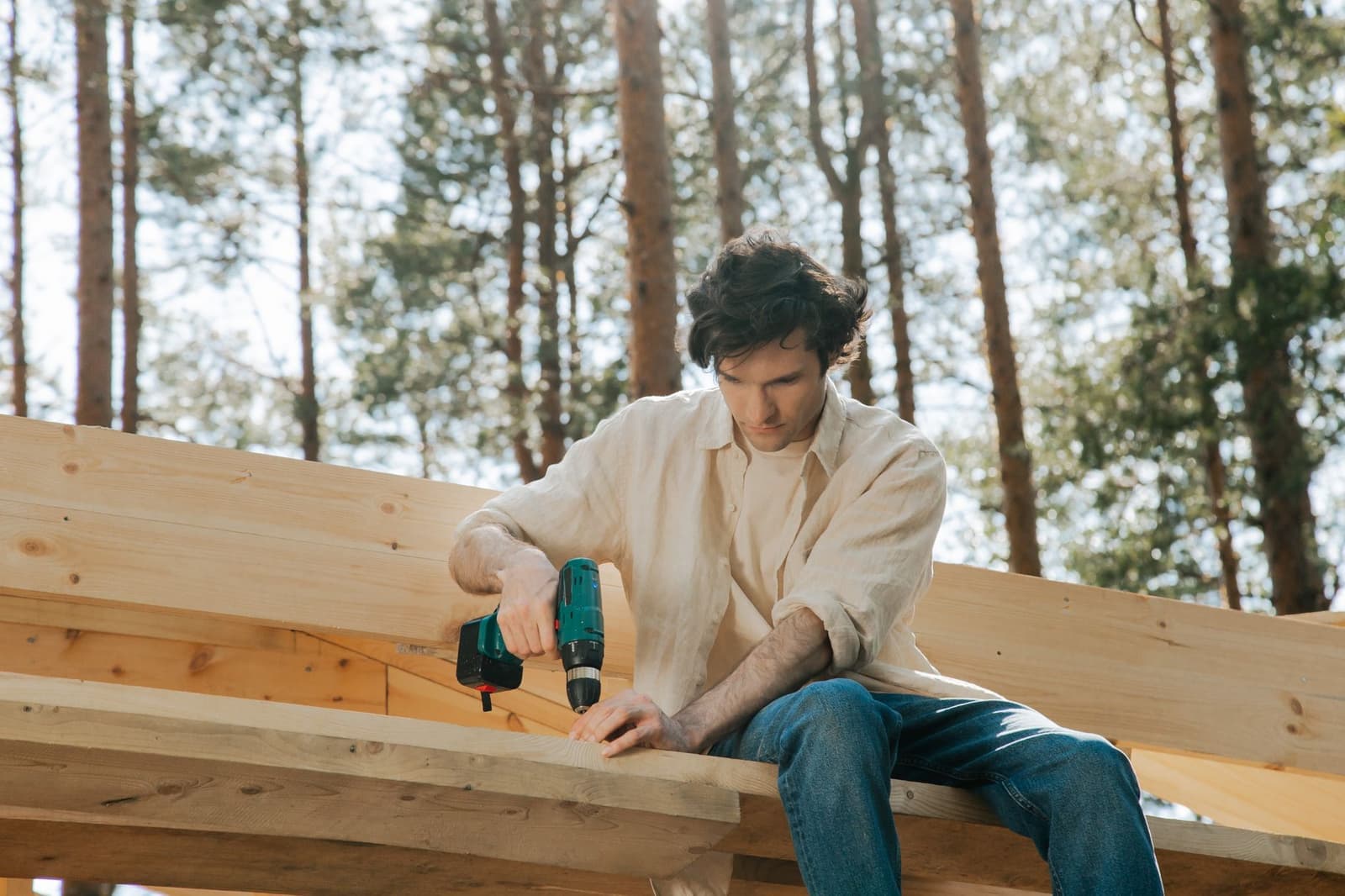 Worker drilling into timber roof framing