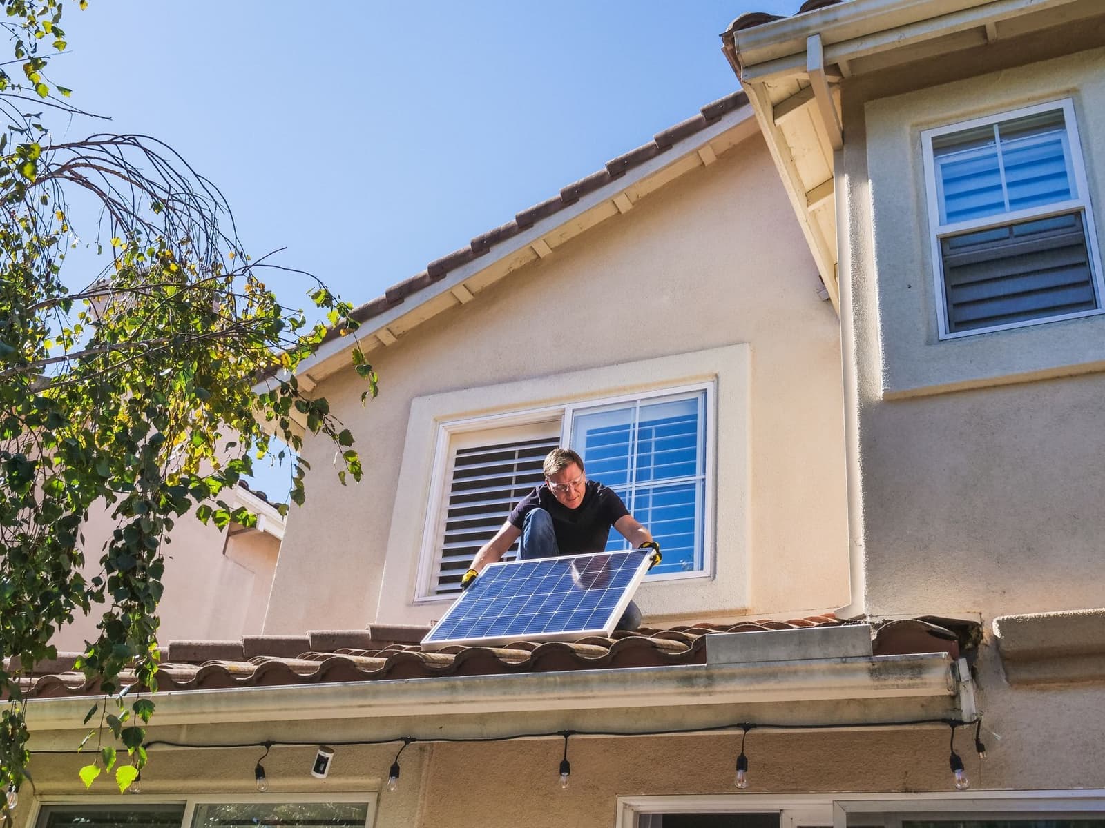 Installer with solar panel on a tile roof