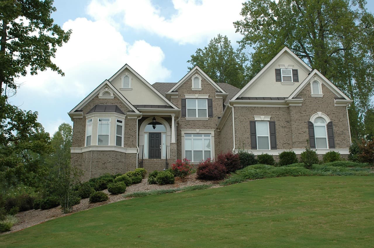 Brick and stone house with shingle roof and lawn