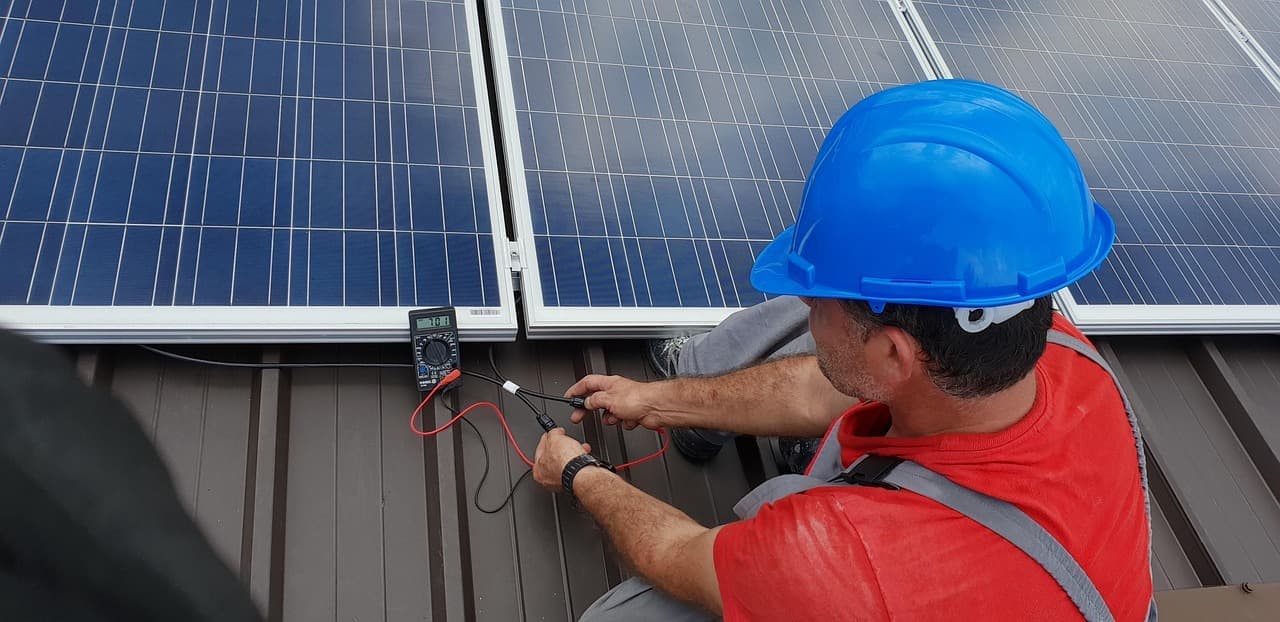Technician testing solar panels on metal roof